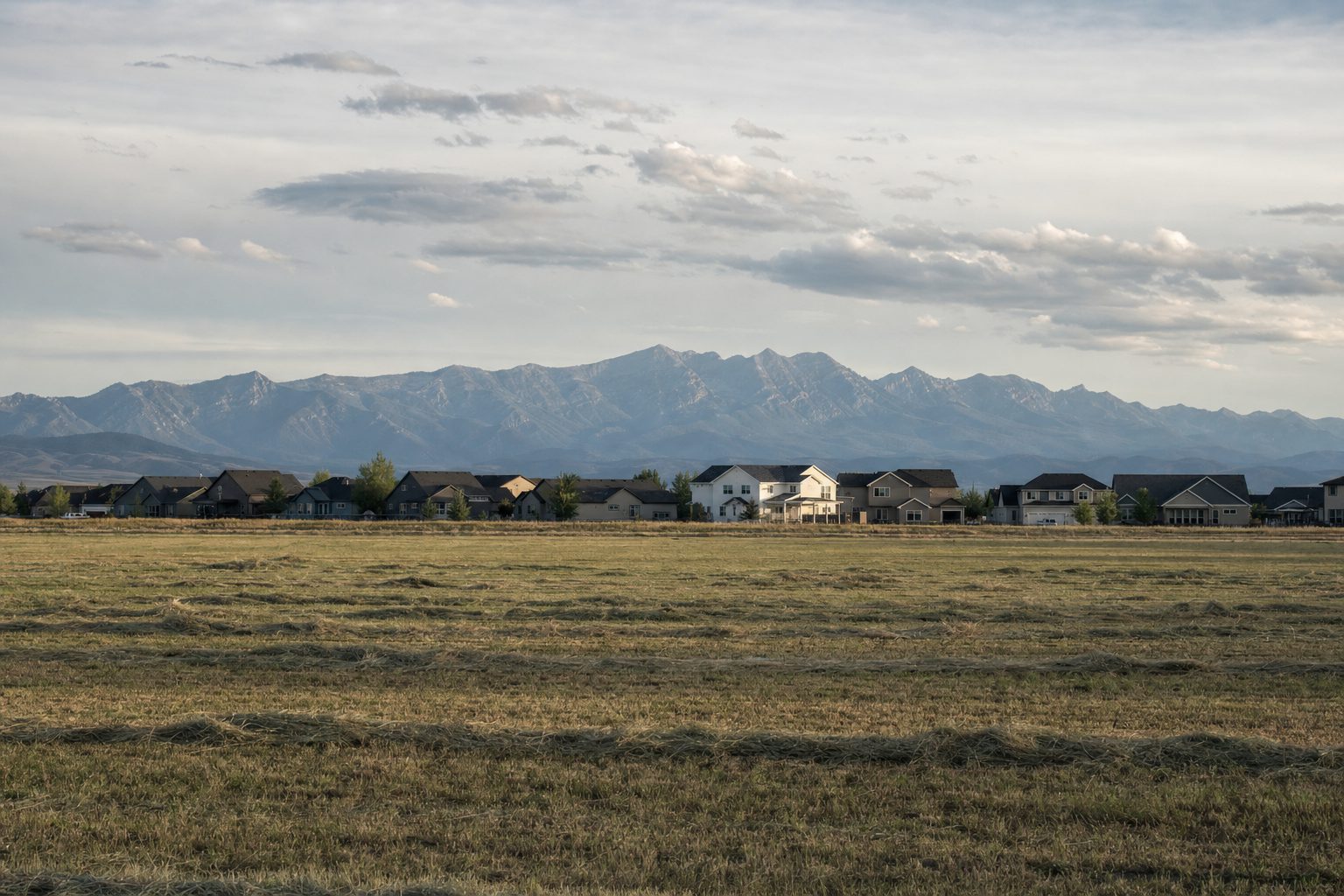 New subdivision homes at the edge of a hayfield near Belgrade, Montana with the Bridger Range behind